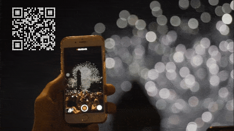 QR code displayed by drones in the night sky during a live event, captured on a smartphone by the audience.